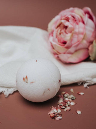 Handmade bathbomb with a peony and a towel on the background